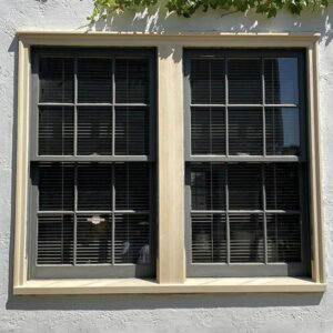 Faded black window with multiple panes, new wood framing, and black blinds inside.