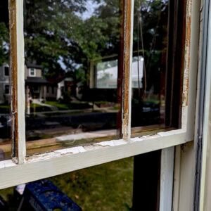 Old wooden window frame with peeling paint and weathered glass panes for restoration.