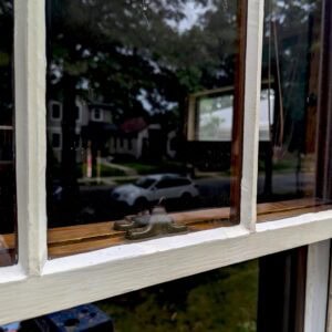Restored wooden window with brass latches and panes, showcasing professional window restoration services.