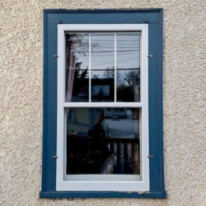 Restored double-hung window with blue trim for home improvement and historic preservation.