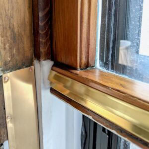 Restoring wooden window frame with fresh paint and sealing for improved insulation and aesthetics.