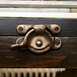 Antique window latch detail on restored wood window frame.