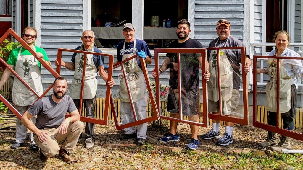 Repaired window frames workshop team participating in window restoration project in front of a house.