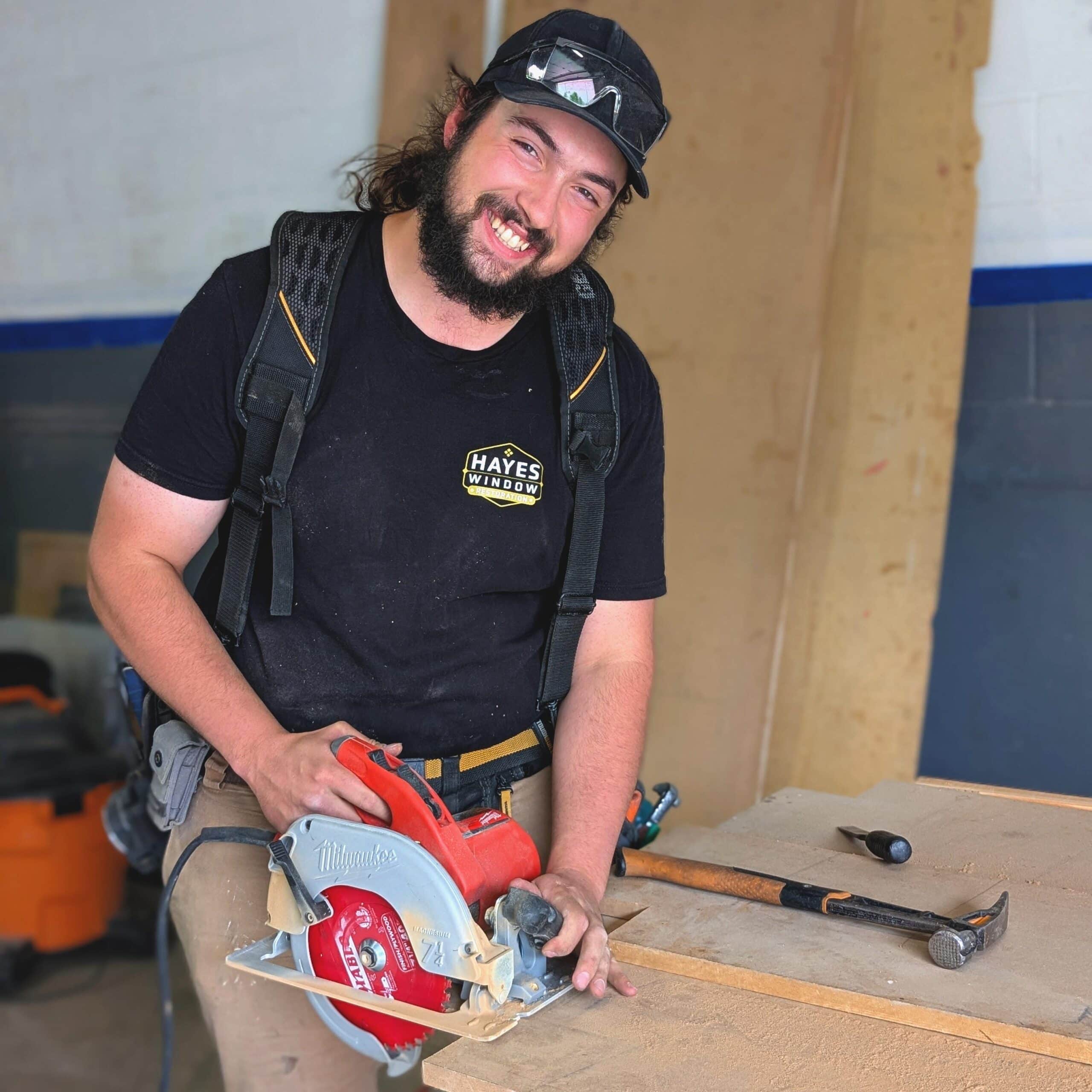 Professional window restoration craftsman using a circular saw for custom wood window repair and restoration.