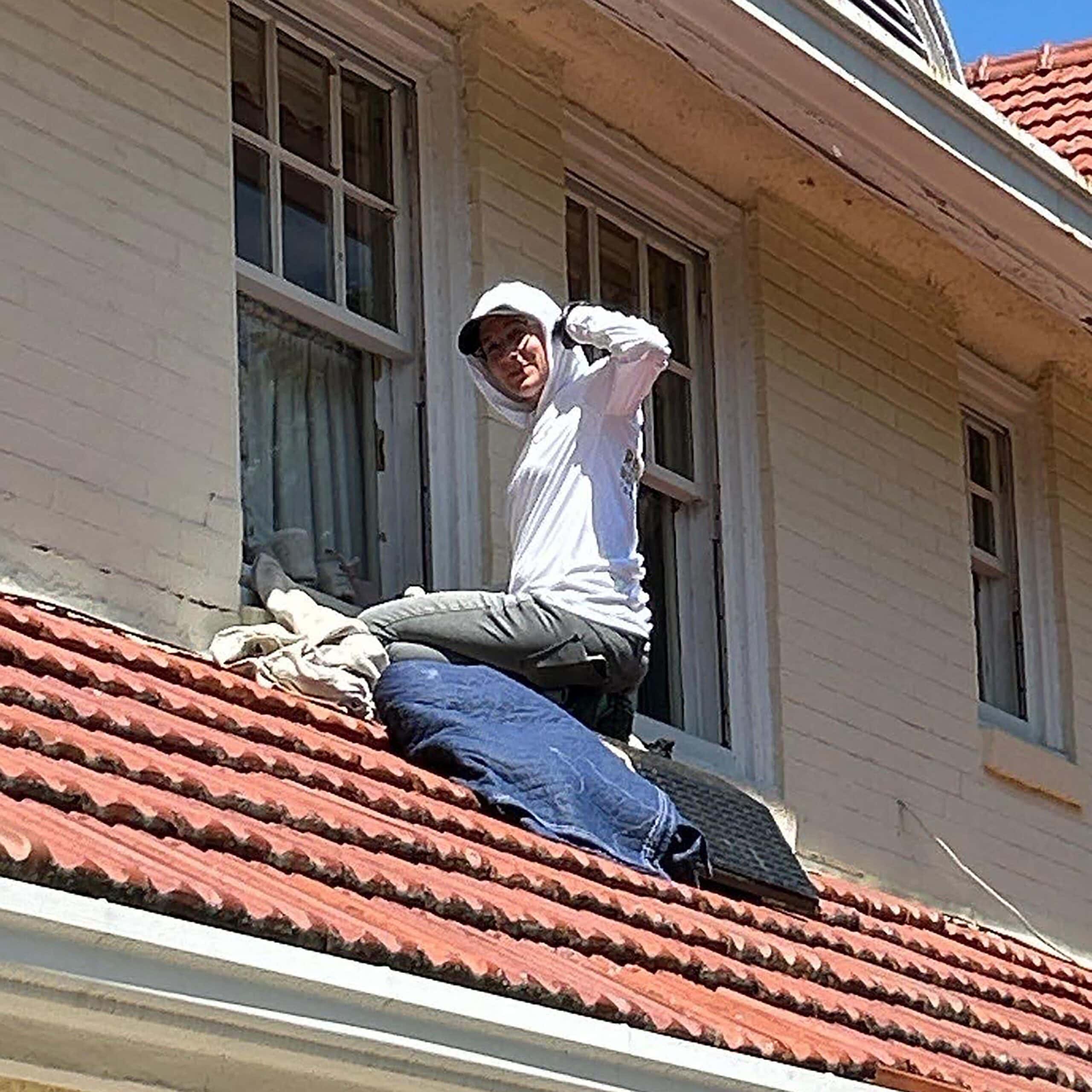 Crane worker repairing or restoring a building's window during Hayes Window Restoration project.
