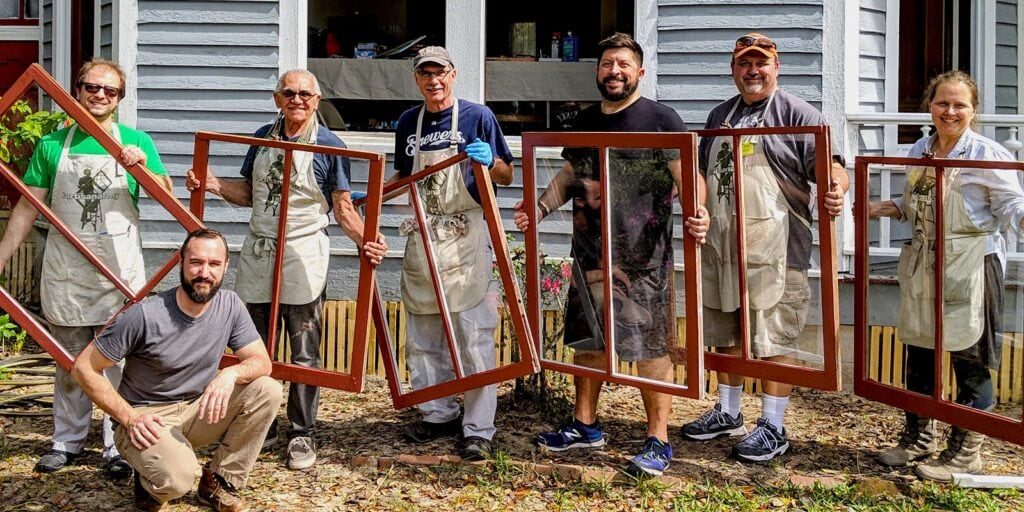 Repaired window frames workshop team participating in window restoration project in front of a house.