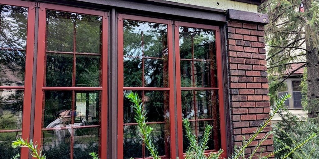 Refinished red brick window frames with restored wooden sash windows for enhanced historic home aesthetics.